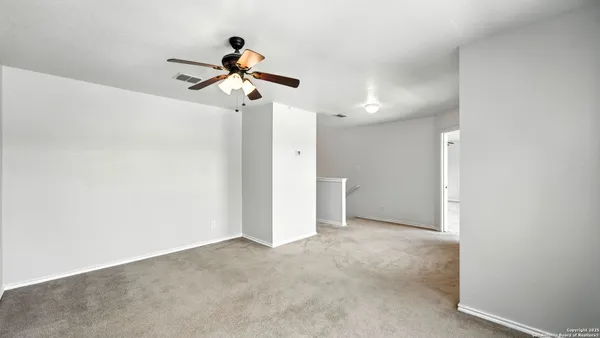 a view of a room with a ceiling fan and carpet