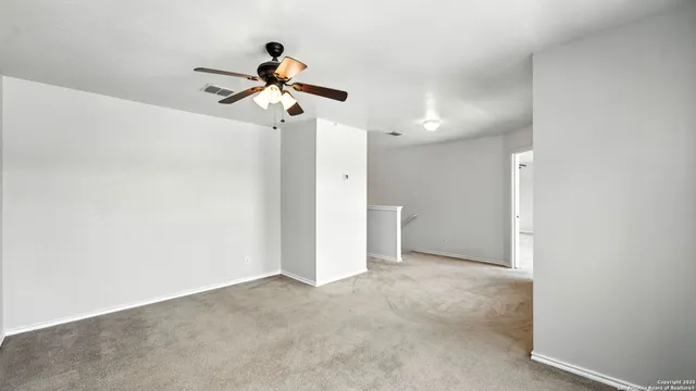 a view of a room with a ceiling fan and carpet