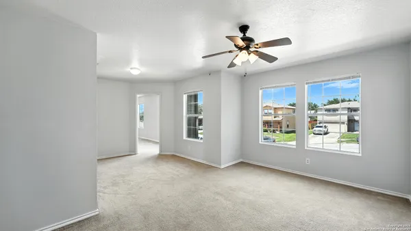 an empty room with windows and ceiling fan