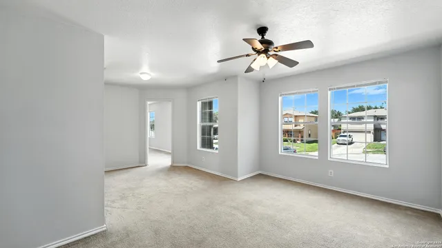 an empty room with windows and ceiling fan