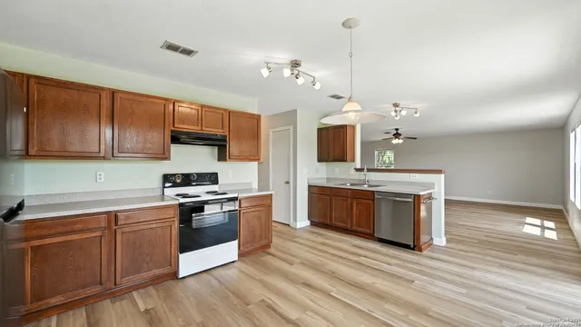 a kitchen with stainless steel appliances granite countertop a stove a sink dishwasher and a microwave oven with white cabinets