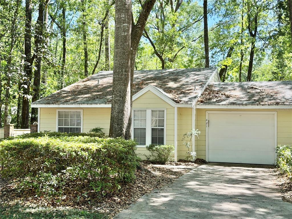 a front view of a house with a garden and tree