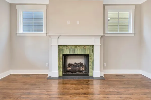 a view of an empty room with wooden floor and a fireplace