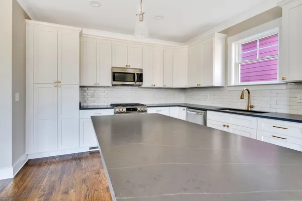 a kitchen with stainless steel appliances granite countertop a sink a stove and microwave