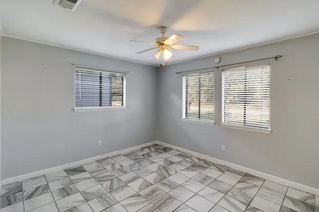 a view of an empty room with window and chandelier fan