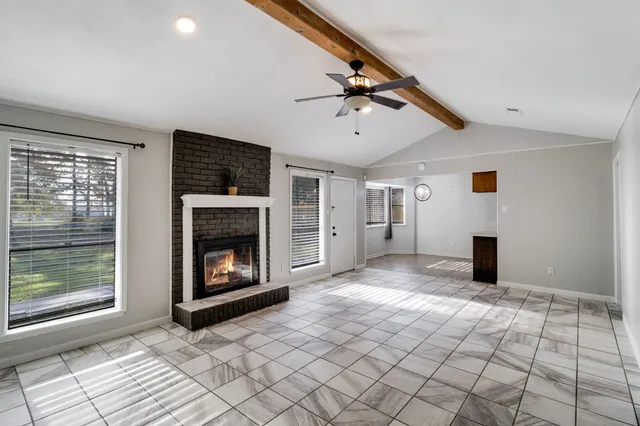 a view of an empty room with window and fire place