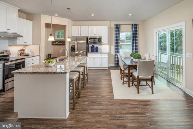 a living room with stainless steel appliances granite countertop furniture wooden floor and a kitchen view