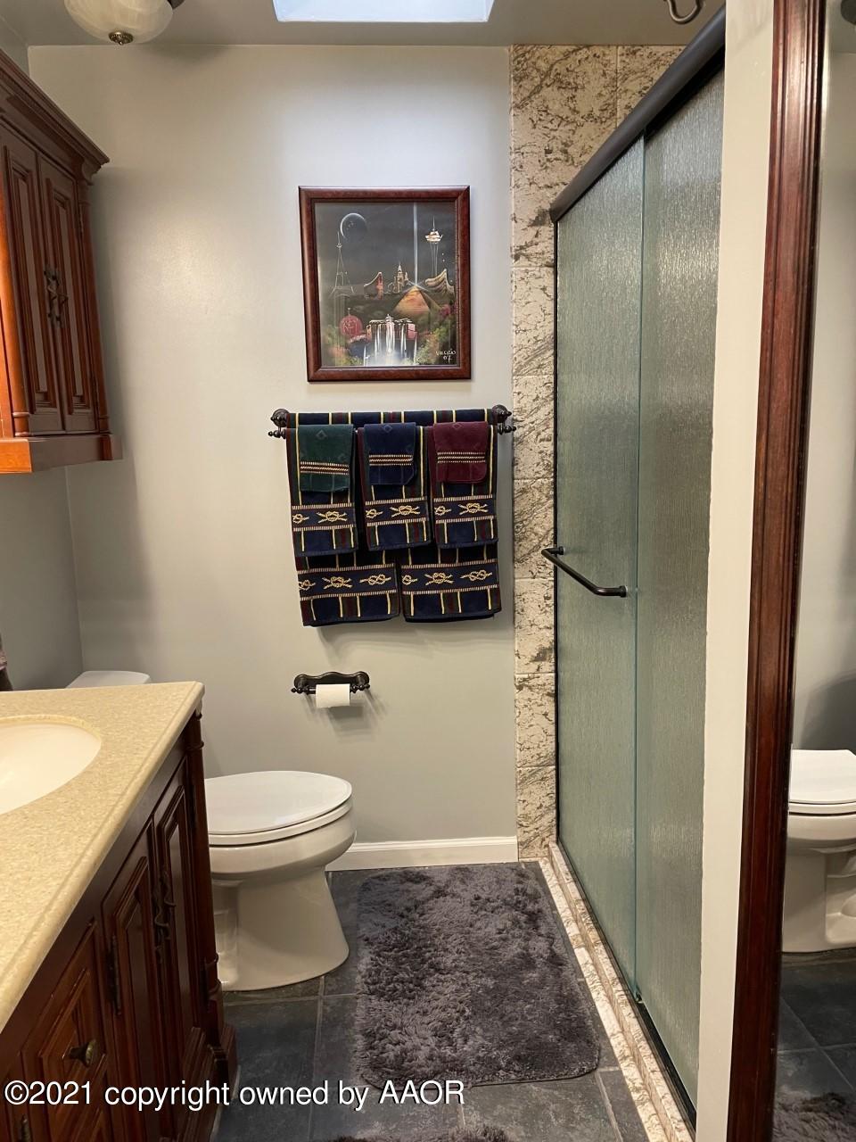 5003 Parker Street Amarillo, TX 79110 - Photo 14 of 20 a bathroom with a toilet a sink and a shower