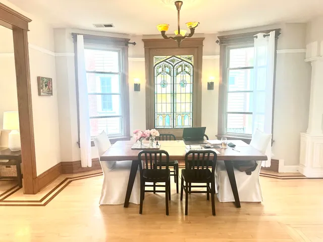 a view of a dining room with furniture a chandelier and large windows