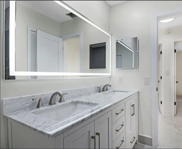 a bathroom with double sink and a mirror