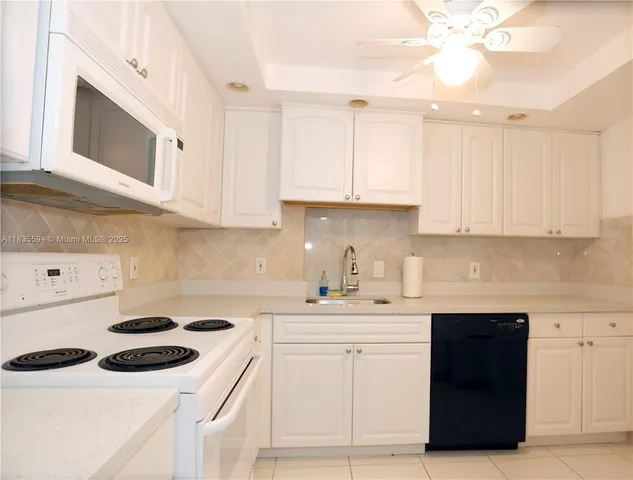 a kitchen with a sink dishwasher stove and white cabinets