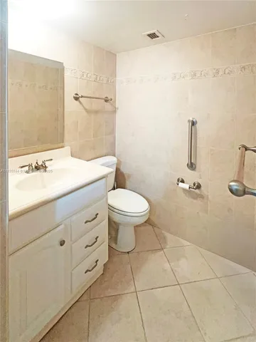 a bathroom with a granite countertop sink a toilet and a mirror