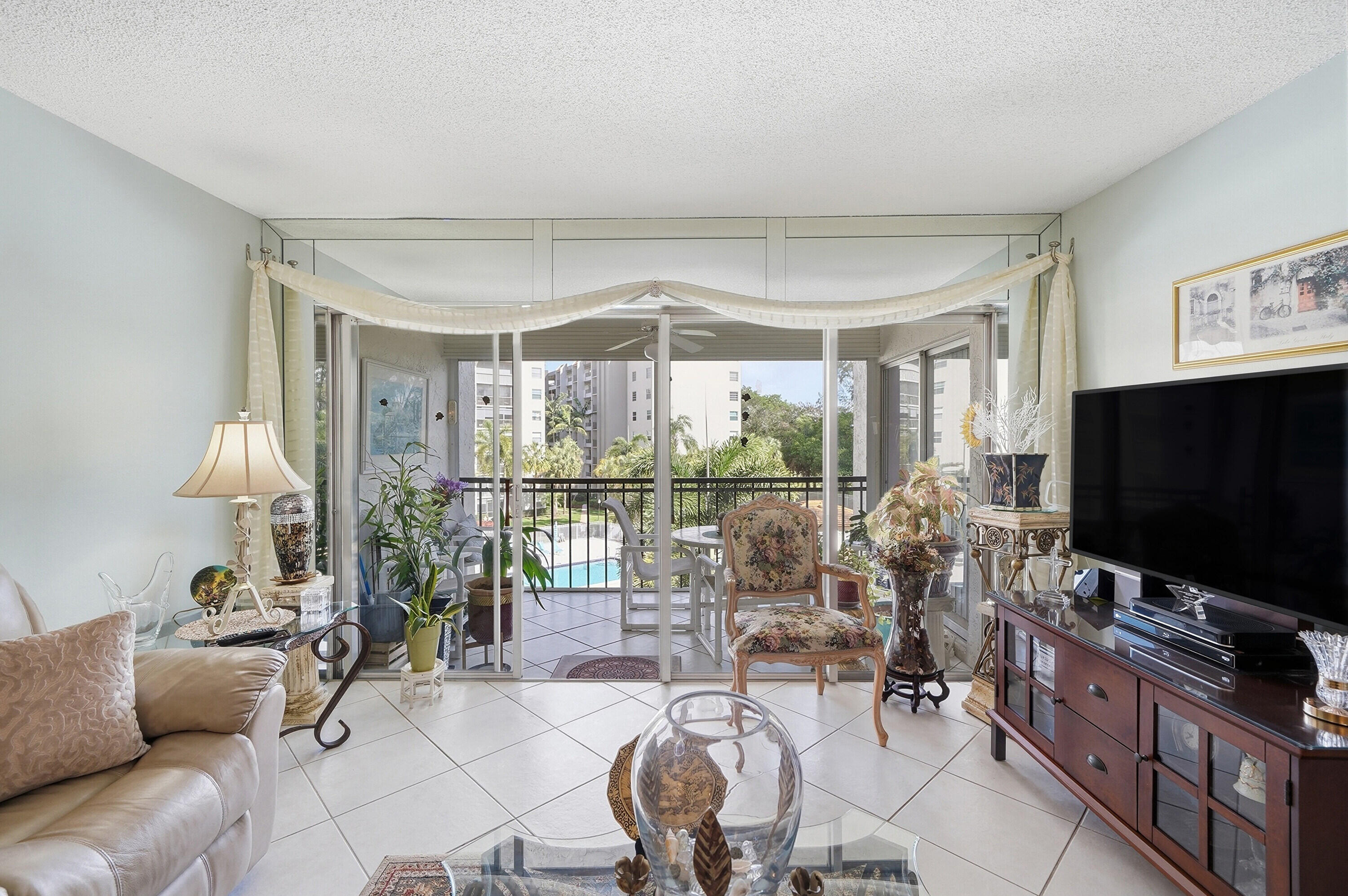 3920 Inverrary Boulevard, Unit 403C Lauderhill, FL 33319 - Photo 13 of 29 a living room with furniture a flat screen tv and a large window