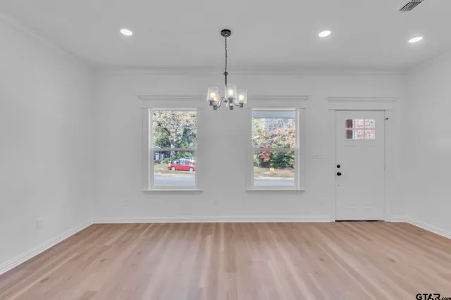 an empty room with window chandelier fan and windows