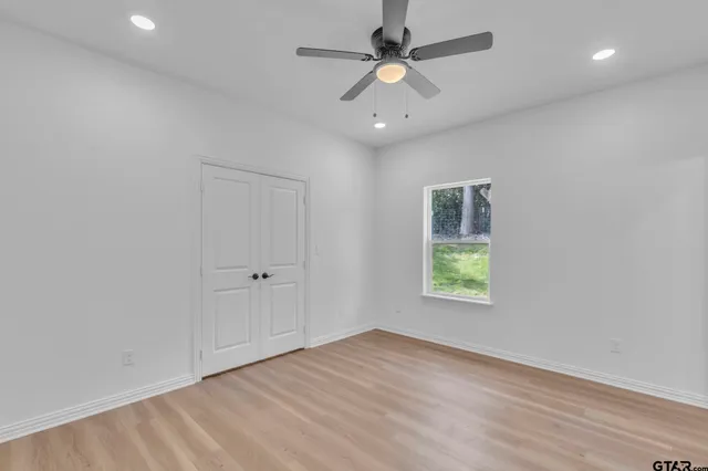 an empty room with a window and a ceiling fan