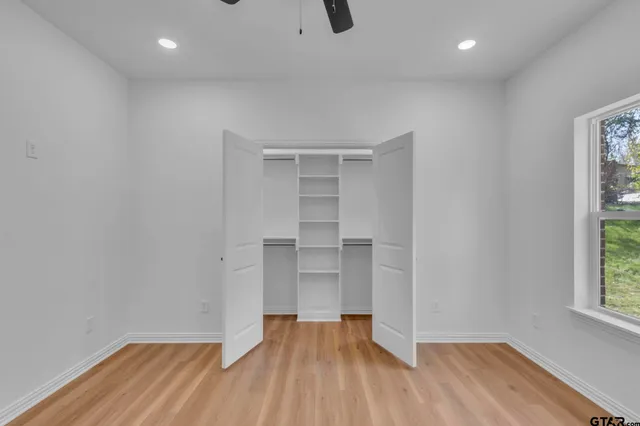 a view of empty room with wooden floor and fan