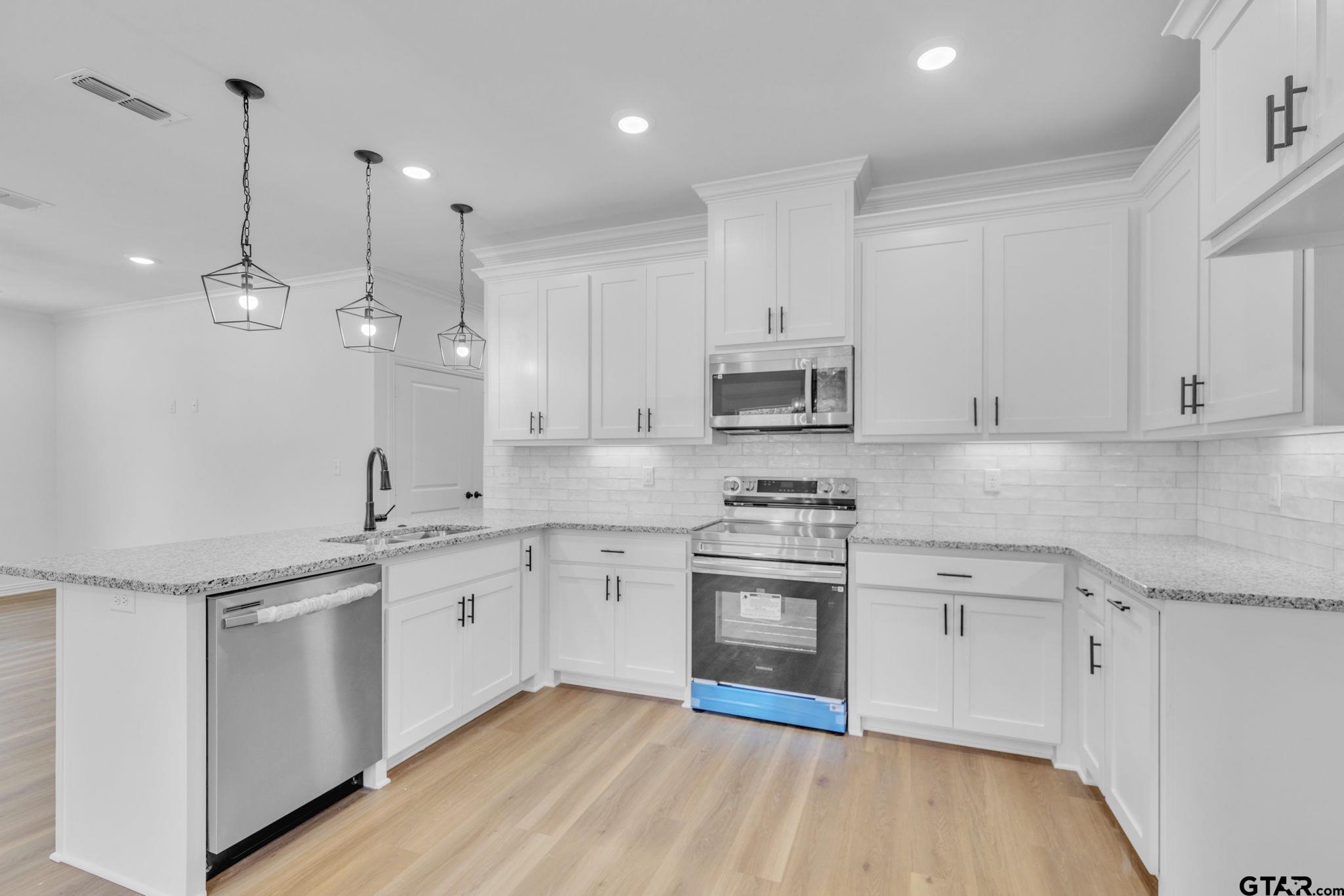 1410 West Connally Street Tyler, TX 75701 - Photo 8 of 29 a kitchen with stainless steel appliances granite countertop a sink a stove a refrigerator and white cabinets with wooden floor