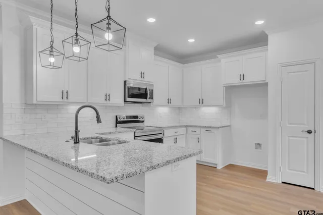 a kitchen with stainless steel appliances granite countertop a sink a stove top oven a counter space and cabinets