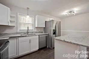 a kitchen with granite countertop white cabinets stove top oven and microwave