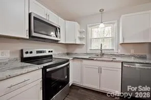 a kitchen with kitchen island granite countertop a refrigerator a sink a stove a microwave a counter top space and cabinets