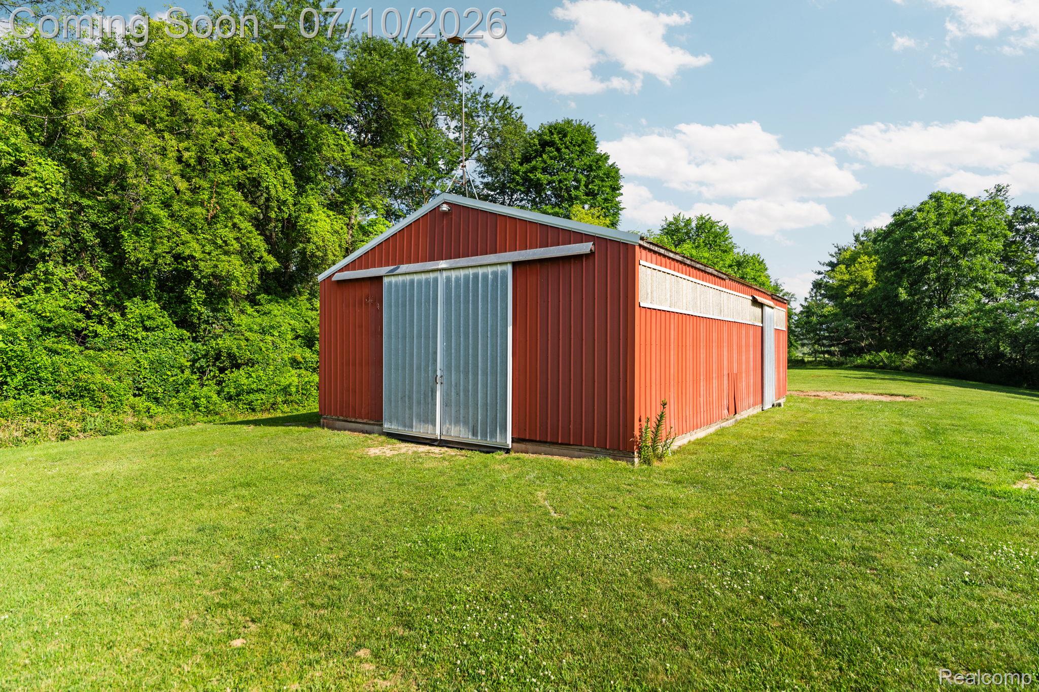 3144 North Nicholson Road Fowlerville, MI 48836 - Photo 27 of 70 Red metal-sided barn with a white trim band and a gabled roof