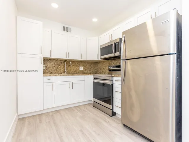 a kitchen with white cabinets and white appliances