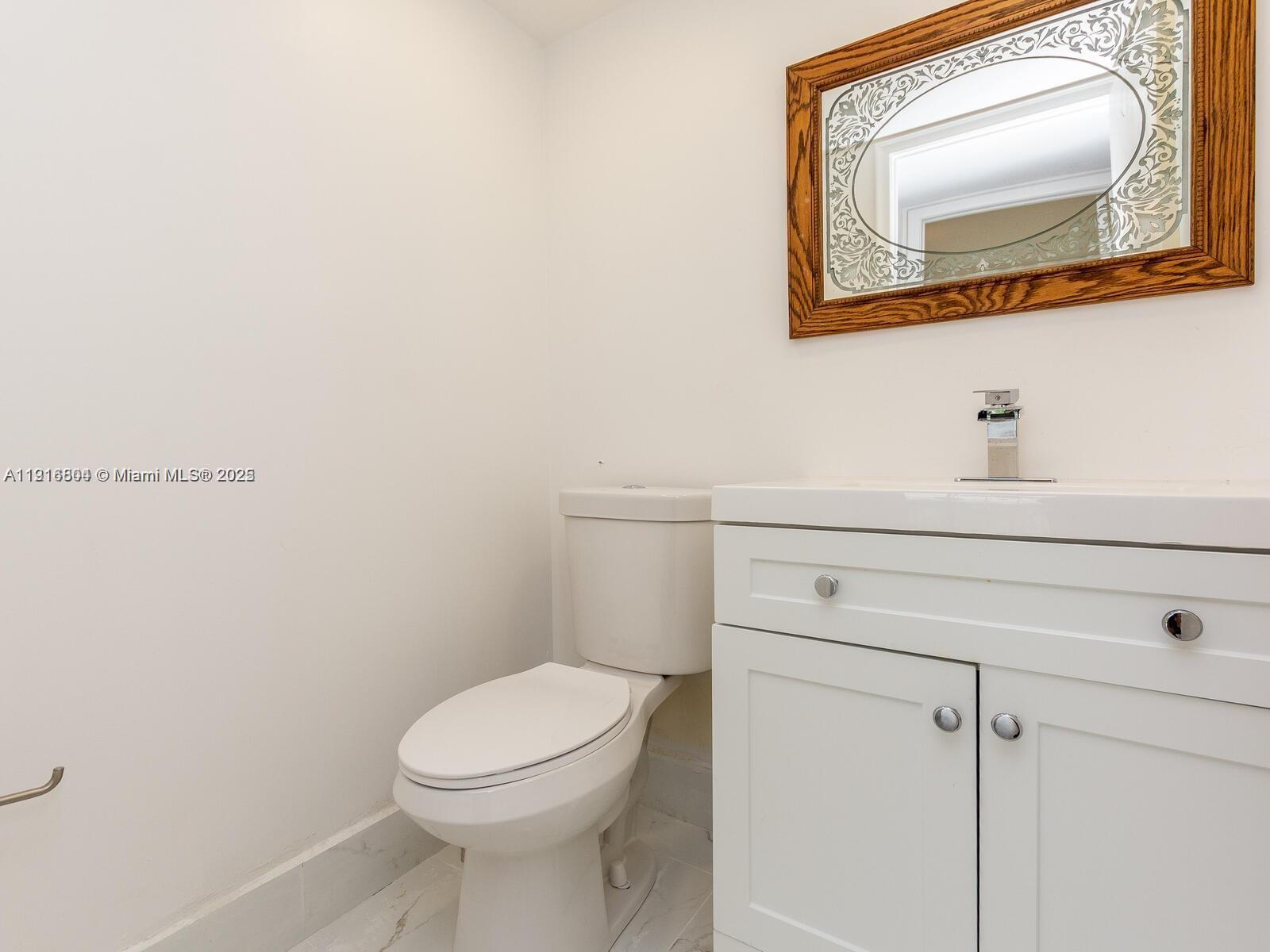 850 Southwest 133rd Terrace, Unit 206B Pembroke Pines, FL 33027 - Photo 6 of 9 a bathroom with a toilet a sink and mirror