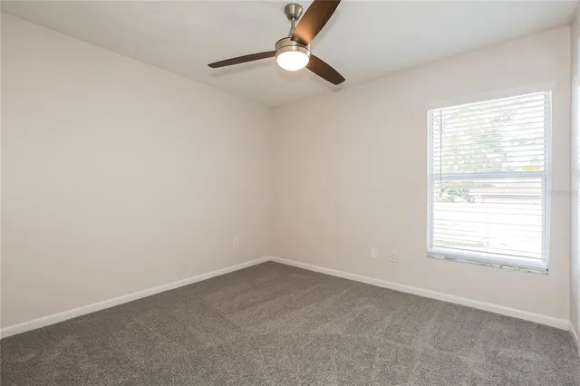 an empty room with a window and a fan