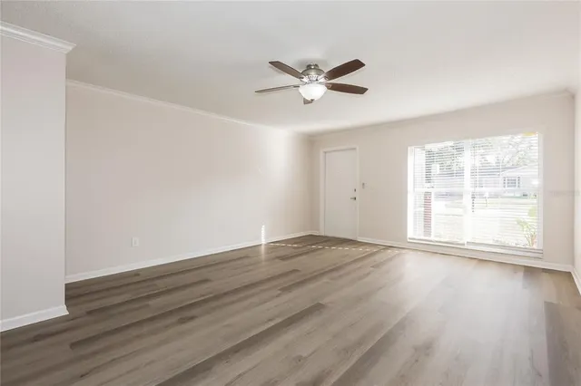 a view of an empty room with wooden floor and a window