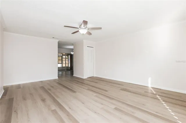 a view of empty room with wooden floor and ceiling fan