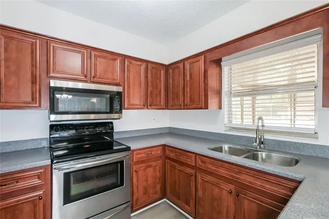 a kitchen with granite countertop a sink cabinets stainless steel appliances and a window