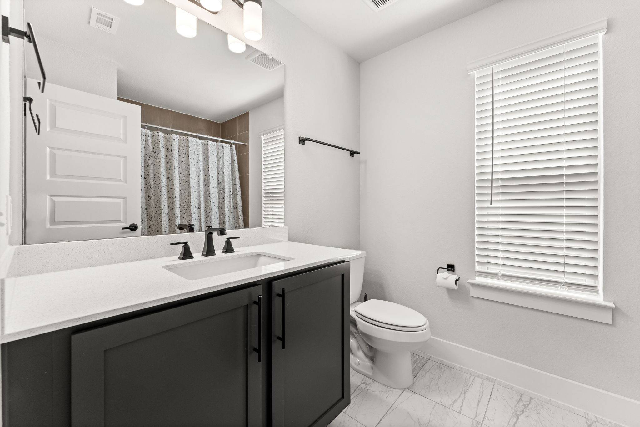 8512 McKamy Drive Austin, TX 78744 - Photo 22 of 28 Stylish guest bathrooms feature quartz vanities and modern finishes.