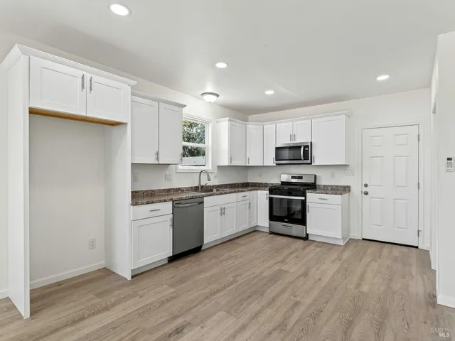 a kitchen with granite countertop white cabinets and stainless steel appliances