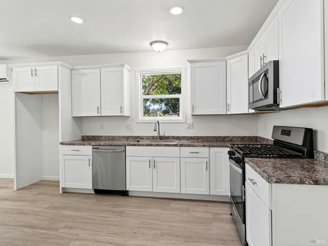 a kitchen with stainless steel appliances granite countertop a stove a sink and a microwave