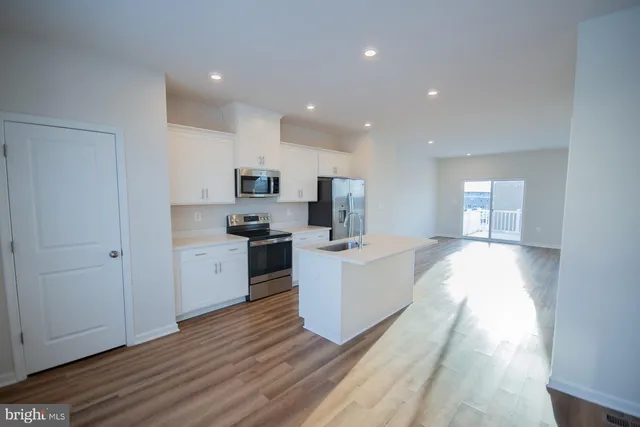 a kitchen with a refrigerator a sink and dishwasher with wooden floor