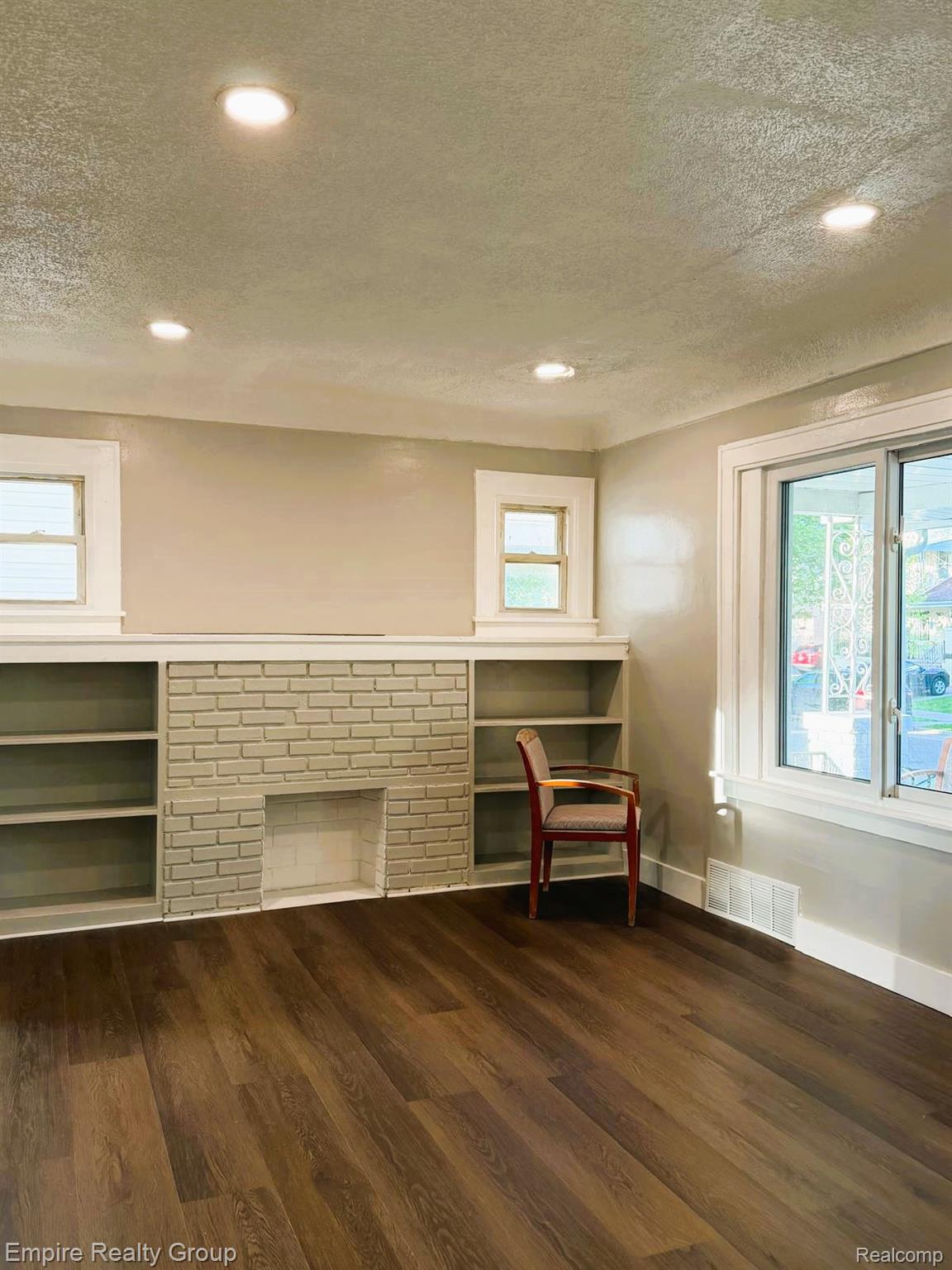 6441 Appoline Street, Unit 1 Dearborn, MI 48126 - Photo 4 of 13 Unfurnished room with a textured ceiling, plenty of natural light, dark wood-type flooring, a fireplace, and recessed lighting