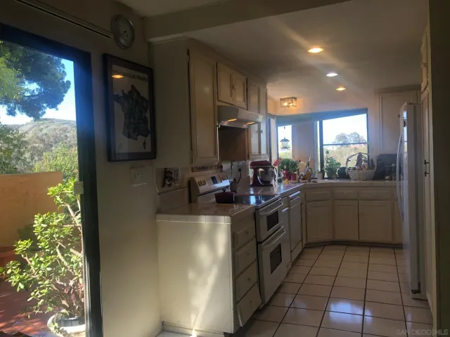a kitchen with a sink stainless steel appliances granite counter tops and a view of living room