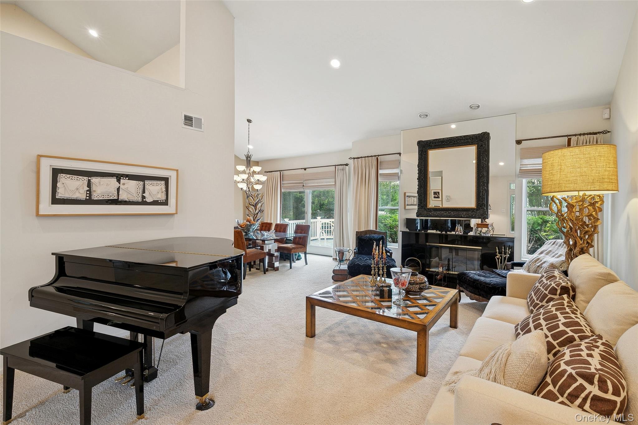 103 Rivendell Court Melville, NY 11747 - Photo 7 of 47 Living room with light colored carpet, recessed lighting, high vaulted ceiling, plenty of natural light, and a chandelier