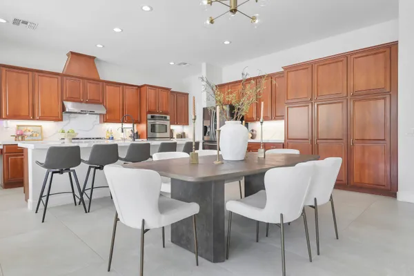 a dining room with stainless steel appliances granite countertop a table chairs and a refrigerator