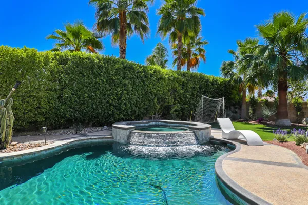 a backyard of a house with table and chairs plants and palm tree