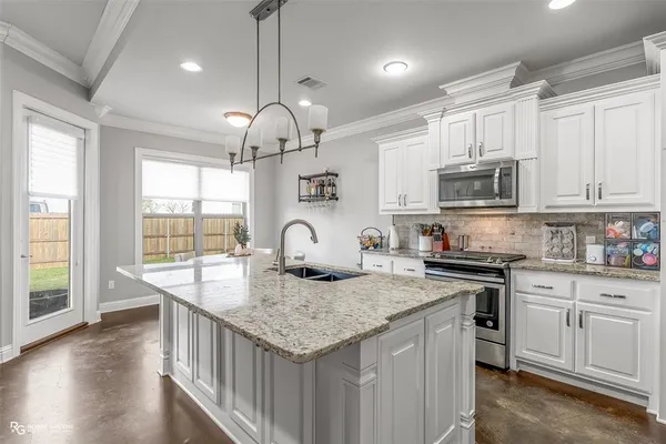 a kitchen with kitchen island granite countertop a stove a sink a center island and wooden floor