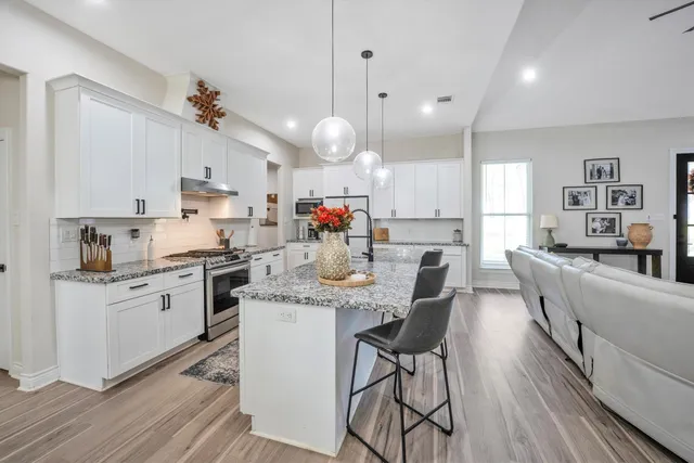 a kitchen with stainless steel appliances kitchen island granite countertop a sink cabinets and wooden floor