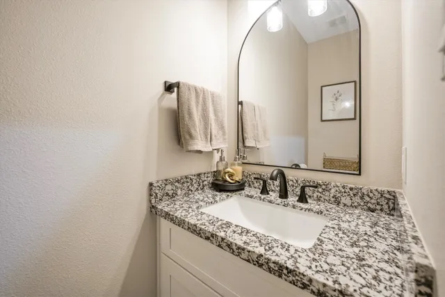 a bathroom with a granite countertop sink and a mirror