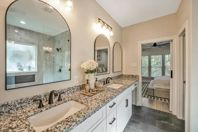 a bathroom with a granite countertop double vanity sink and a mirror