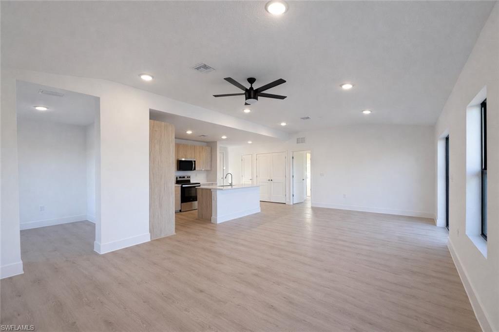 an empty room with wooden floor and a ceiling fan