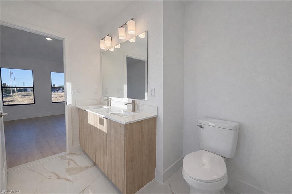 2812 23rd Street Southwest Lehigh Acres, FL 33976 - Photo 8 of 17 a bathroom with a toilet a sink and mirror