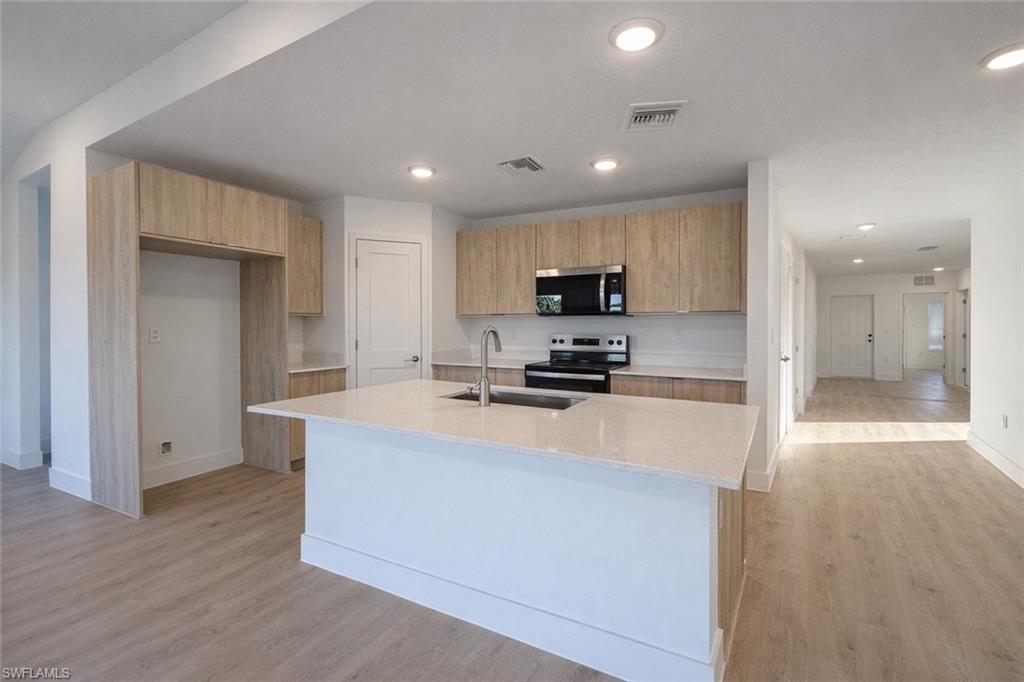 2812 23rd Street Southwest Lehigh Acres, FL 33976 - Photo 3 of 17 a large kitchen with a large counter top stainless steel appliances and cabinets