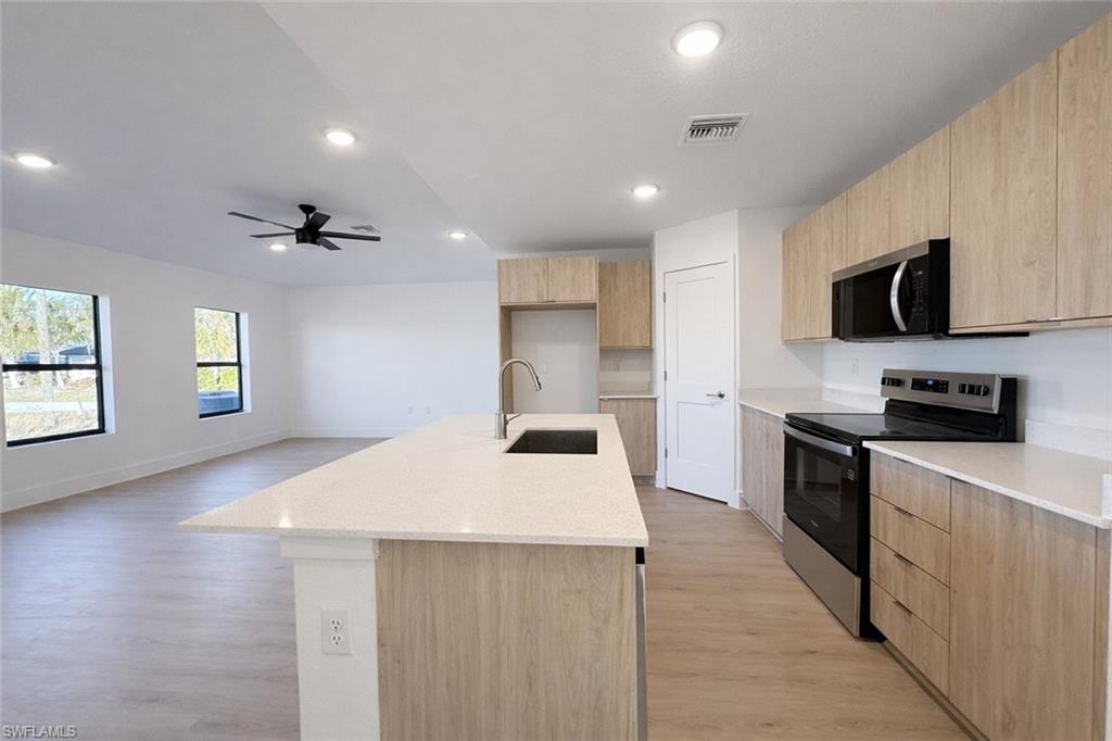 2812 23rd Street Southwest Lehigh Acres, FL 33976 - Photo 4 of 17 a kitchen with stainless steel appliances a stove sink microwave and cabinets
