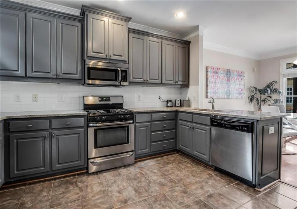 2846 Piedmont Road Northeast, Unit 1 Atlanta, GA 30305 - Photo 12 of 29 a kitchen with stainless steel appliances granite countertop a stove top oven a sink dishwasher and a refrigerator with wooden cabinets