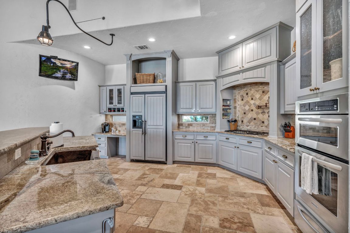 144 Serene Street Spring Branch, TX 78070 - Photo 12 of 37 a kitchen with stainless steel appliances kitchen island granite countertop a refrigerator and a stove top oven